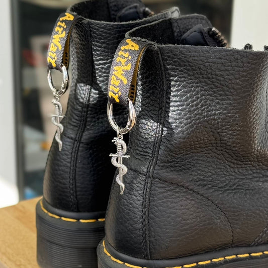 A pair of silver snake sword charms attached to dr marten boots