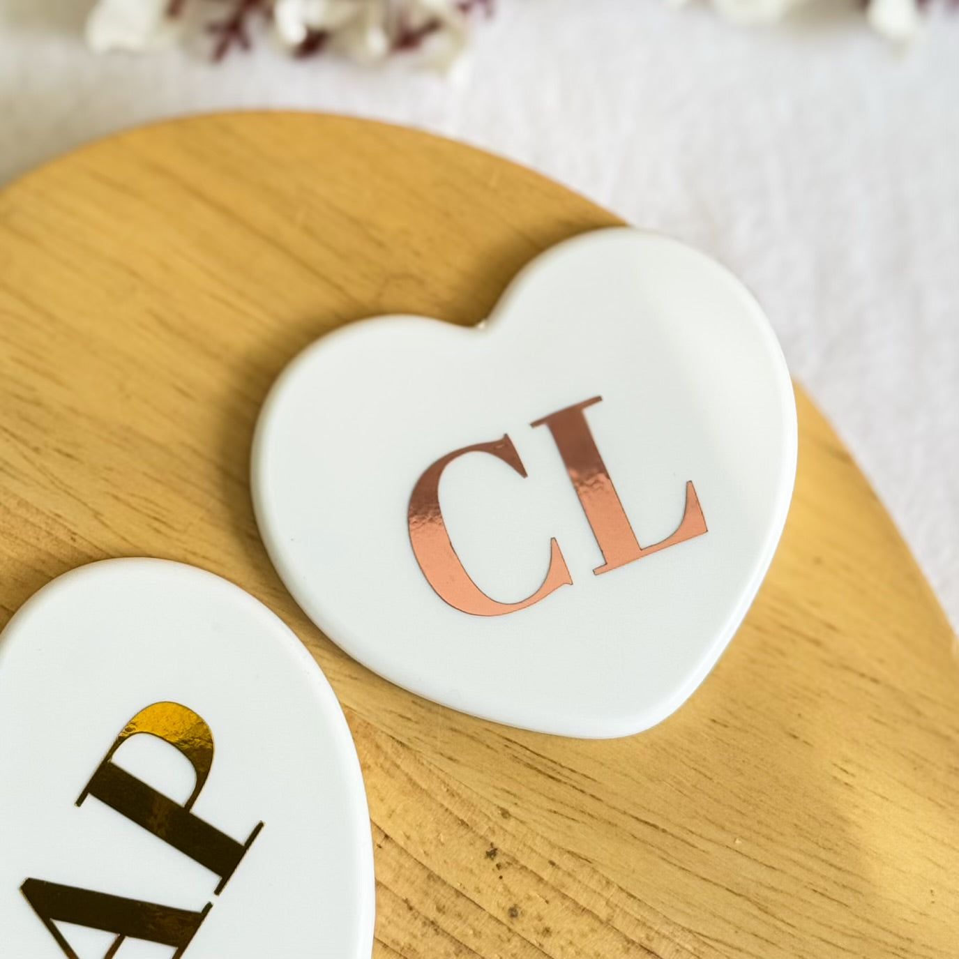 Set of heart-shaped mini mirrors personalised with rose gold initials on wooden surface