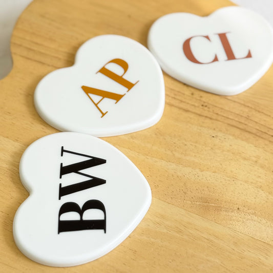 Set of heart-shaped mini mirrors personalised with initials on wooden surface