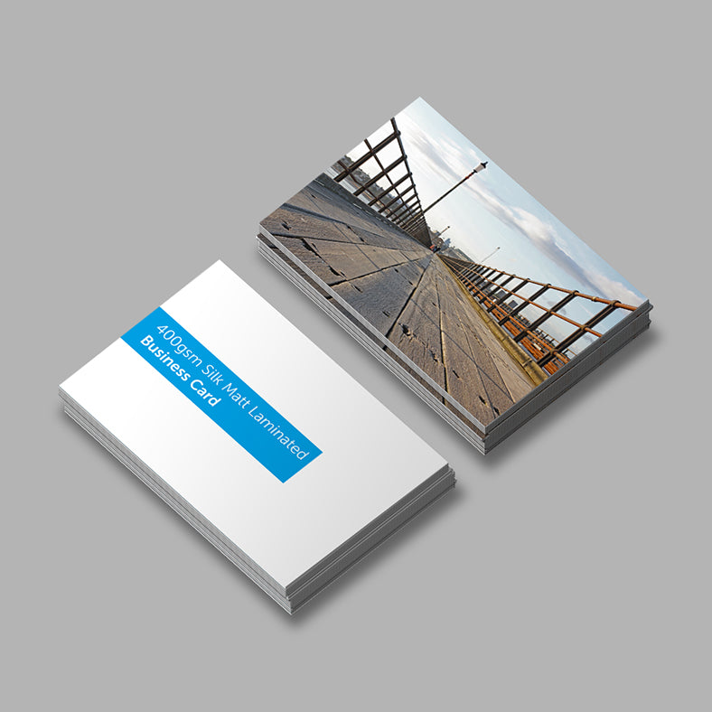 Stack of business cards with a scenic design on one card and text on the other, on a gray background.