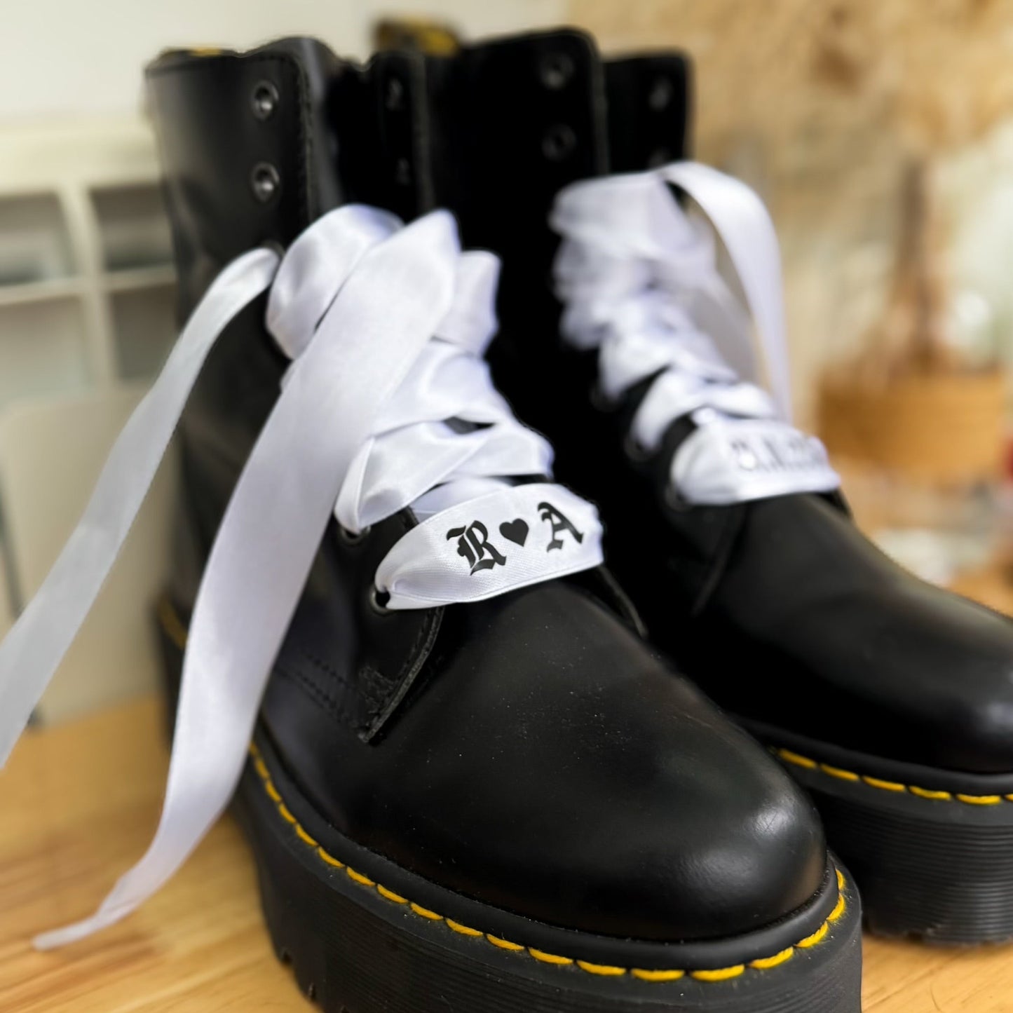 Custom white satin bridal boot laces printed with couple’s initials and wedding date, styled on Dr. Martens for a modern bridal look.