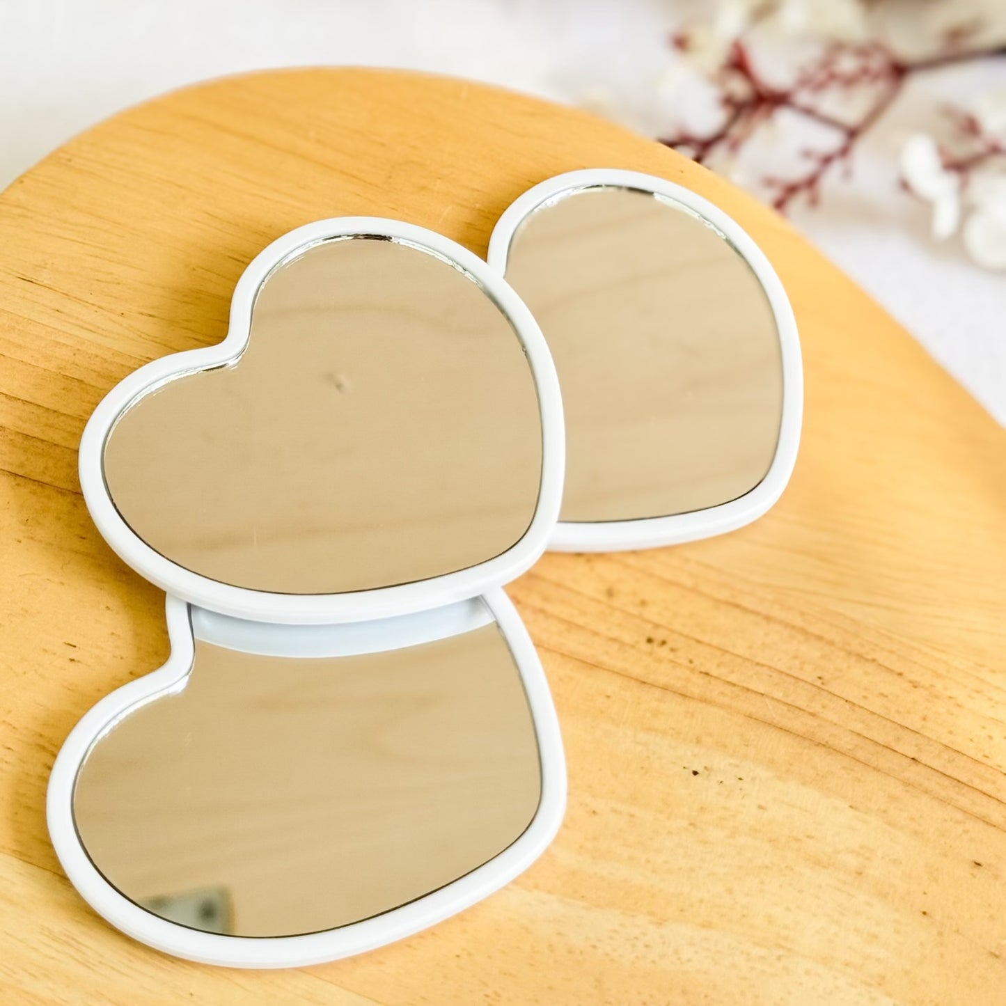 Three heart-shaped mirrors on a wooden surface