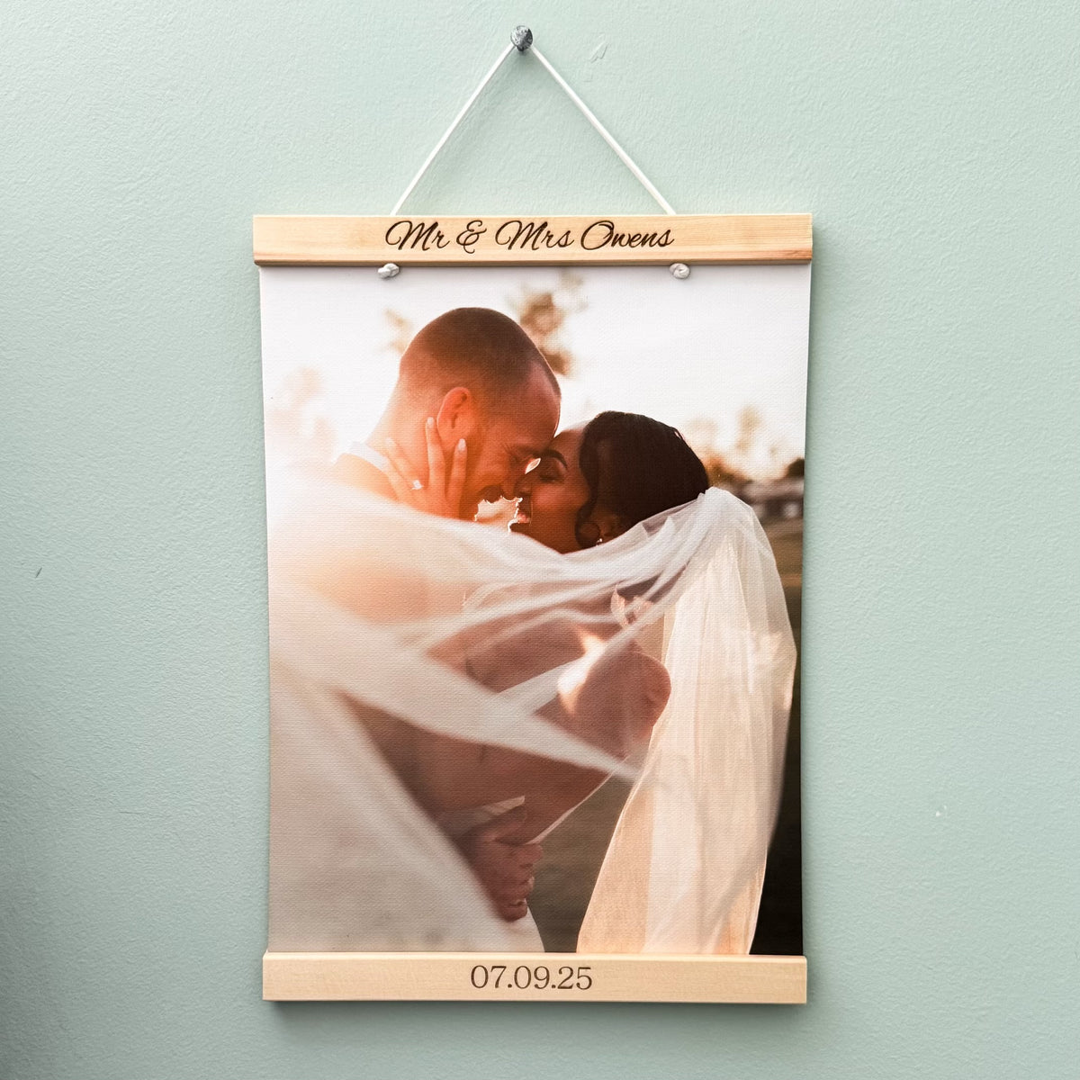 Personalised photo frame with a wedding photo hanging on a light green wall.
