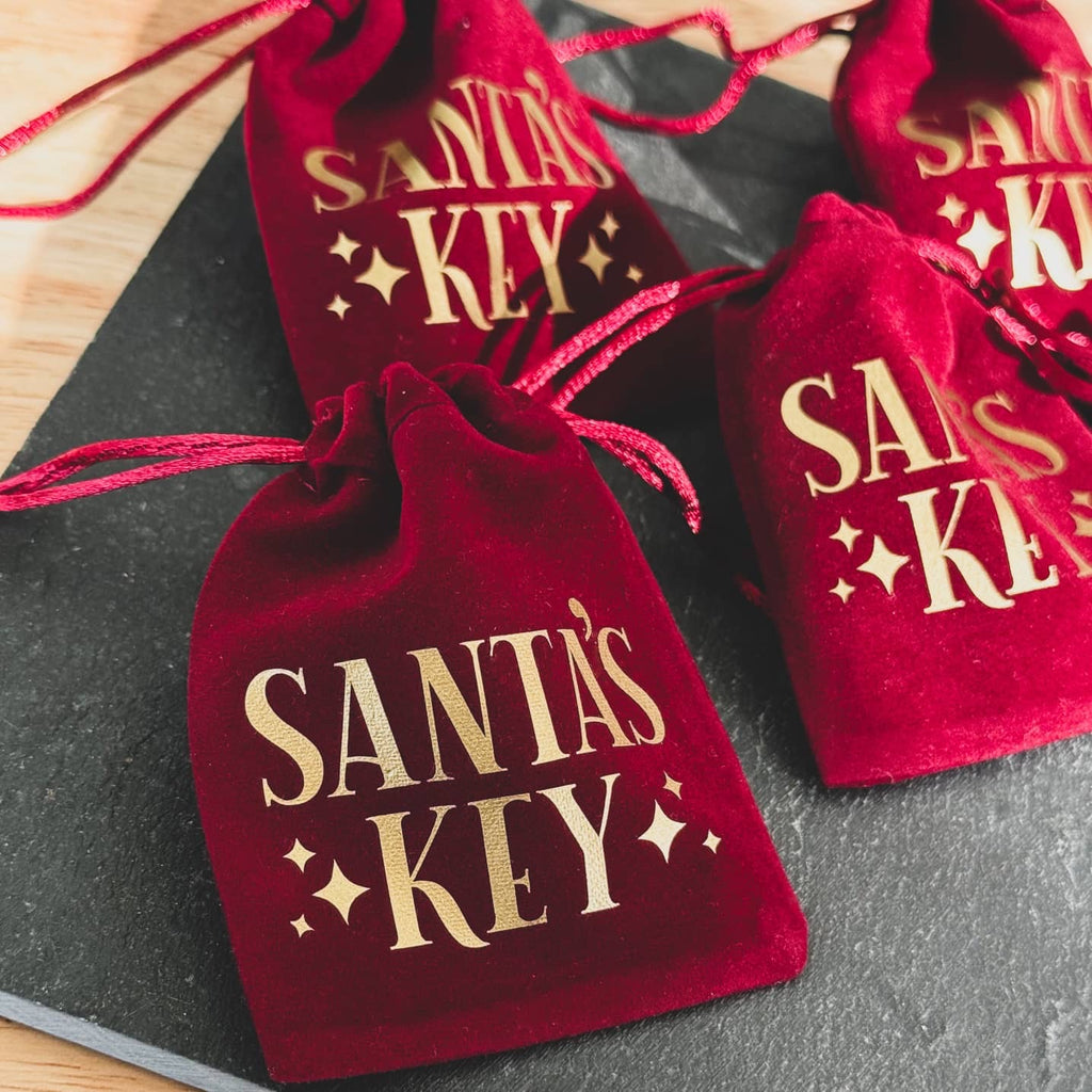 Red velvet Santa's Key bags with gold lettering on slate
