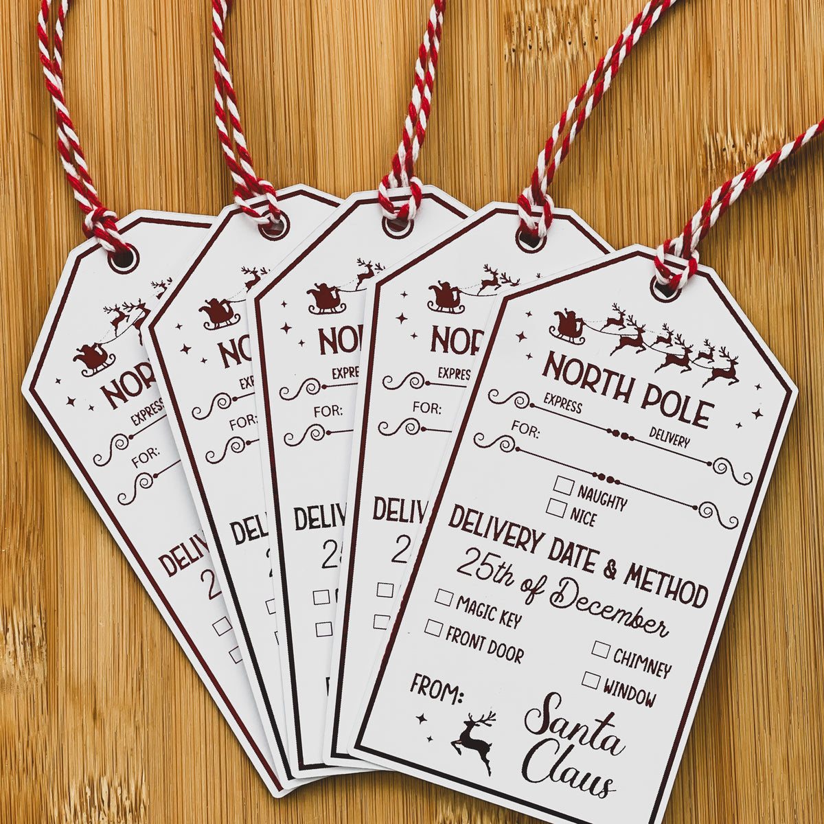 Five North Pole gift tags fanned out with red foil detail