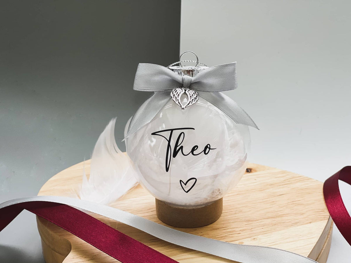 Feather-filled memorial bauble with the name Theo and a grey bow