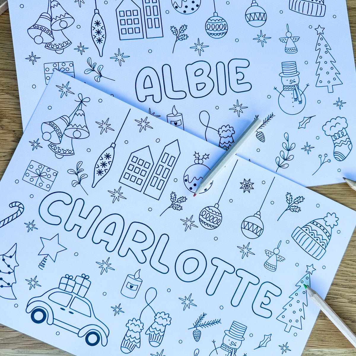 Two personalised Christmas colouring placemats for Albie and Charlotte with a pen