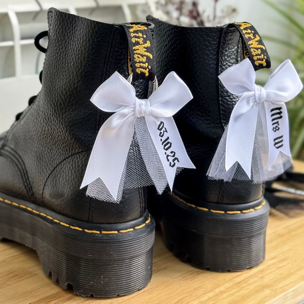 Black boots decorated with attachable boot charm bows with tulle, personalised with name and wedding date