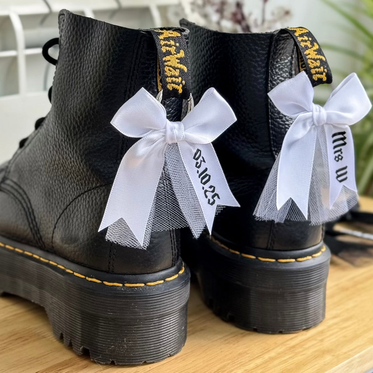 Black boots decorated with attachable boot charm bows with tulle, personalised with name and wedding date