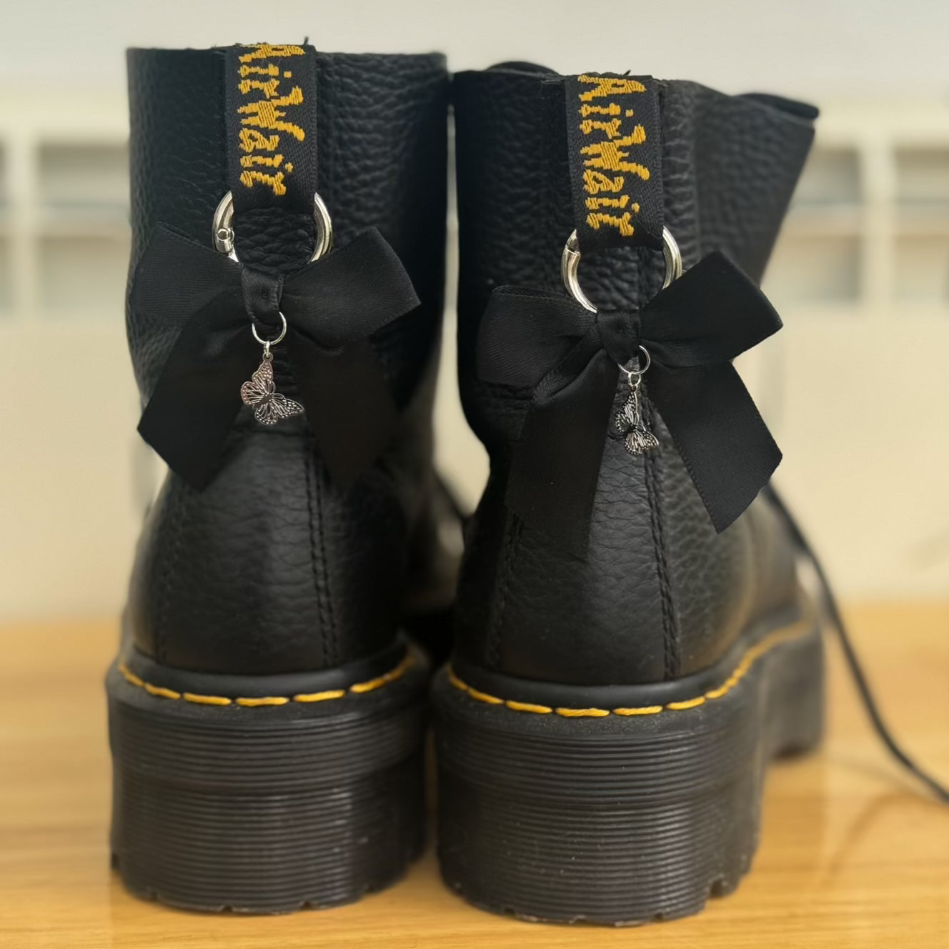 Black boots with black bows and butterfly charms
