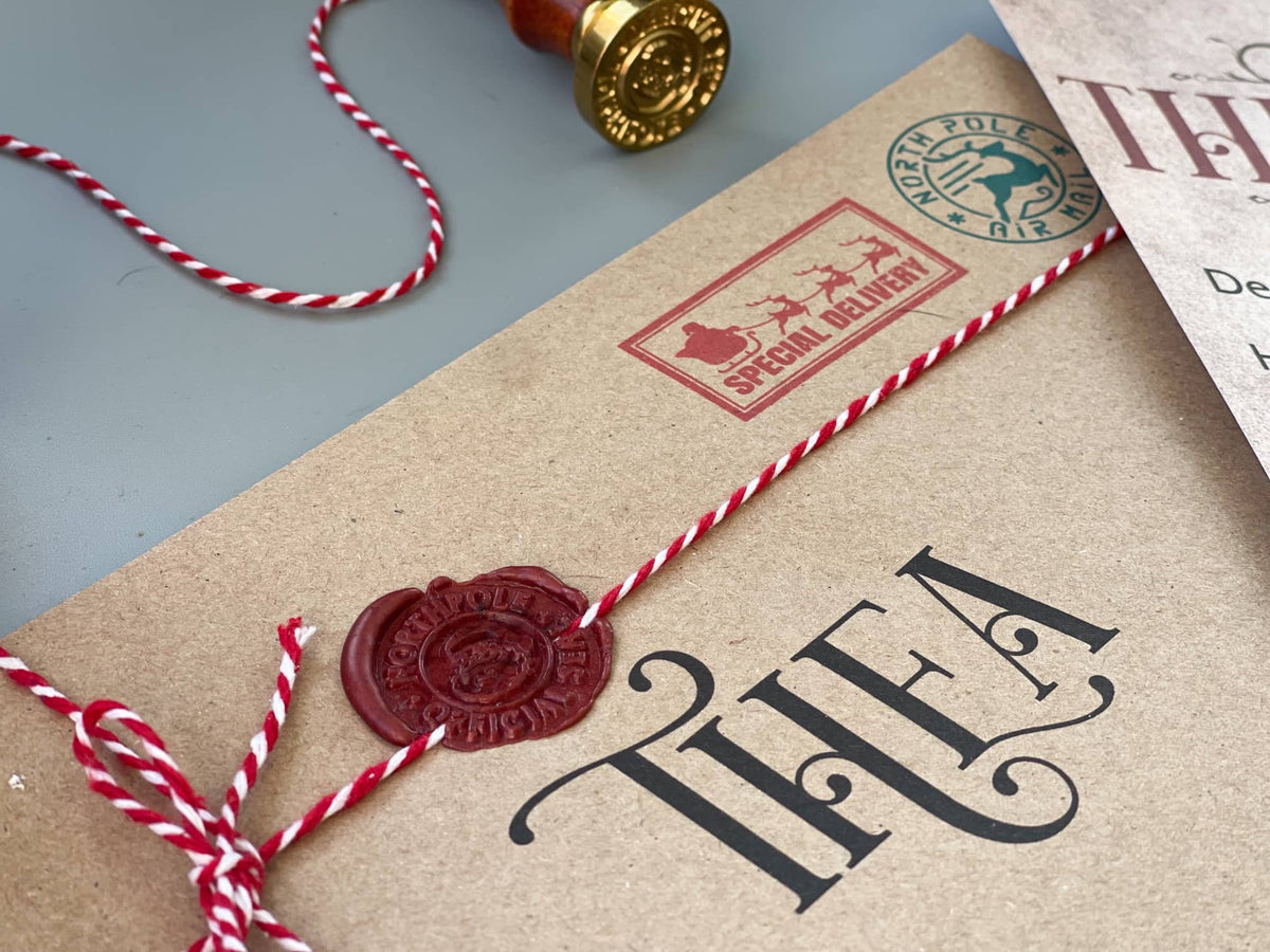 Kraft envelope addressed to Thea with a red wax seal and red and white twine