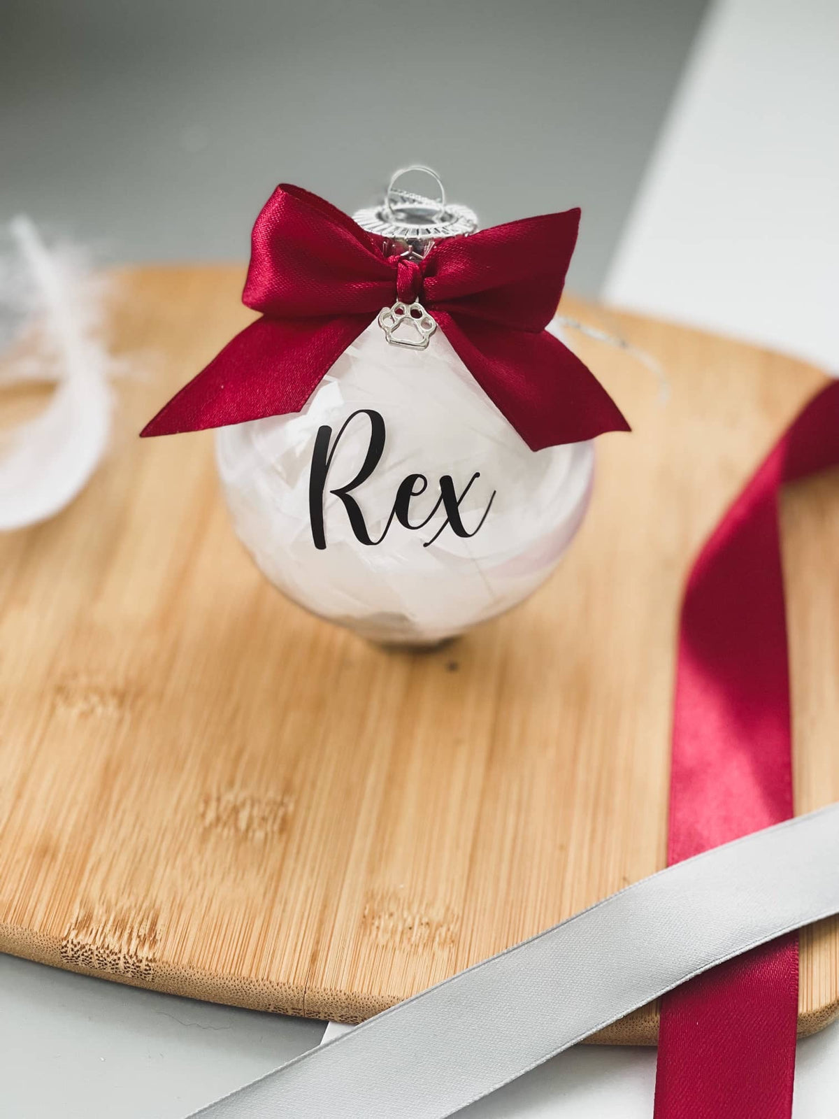 Feather-filled pet memorial bauble with the name Rex and a red bow