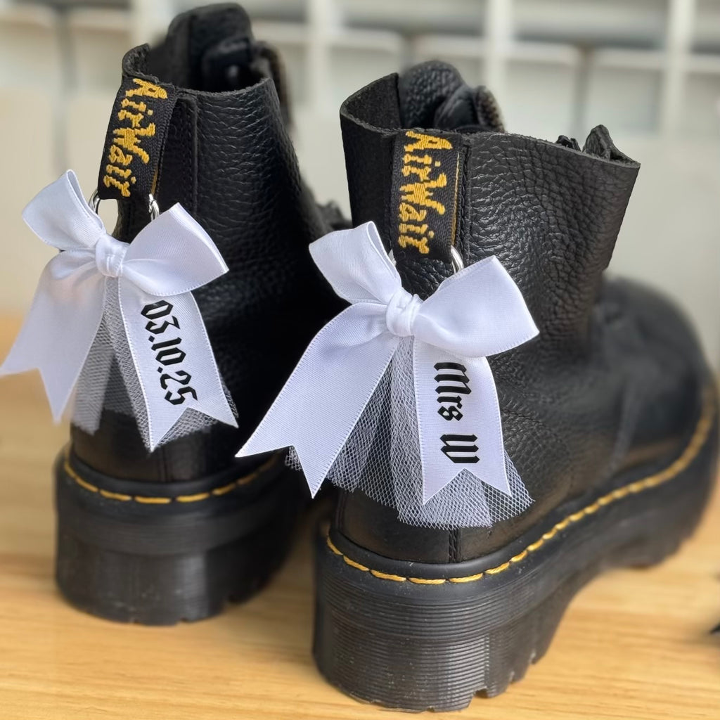 Black boots decorated with attachable boot charm bows with tulle, personalised with name and wedding date