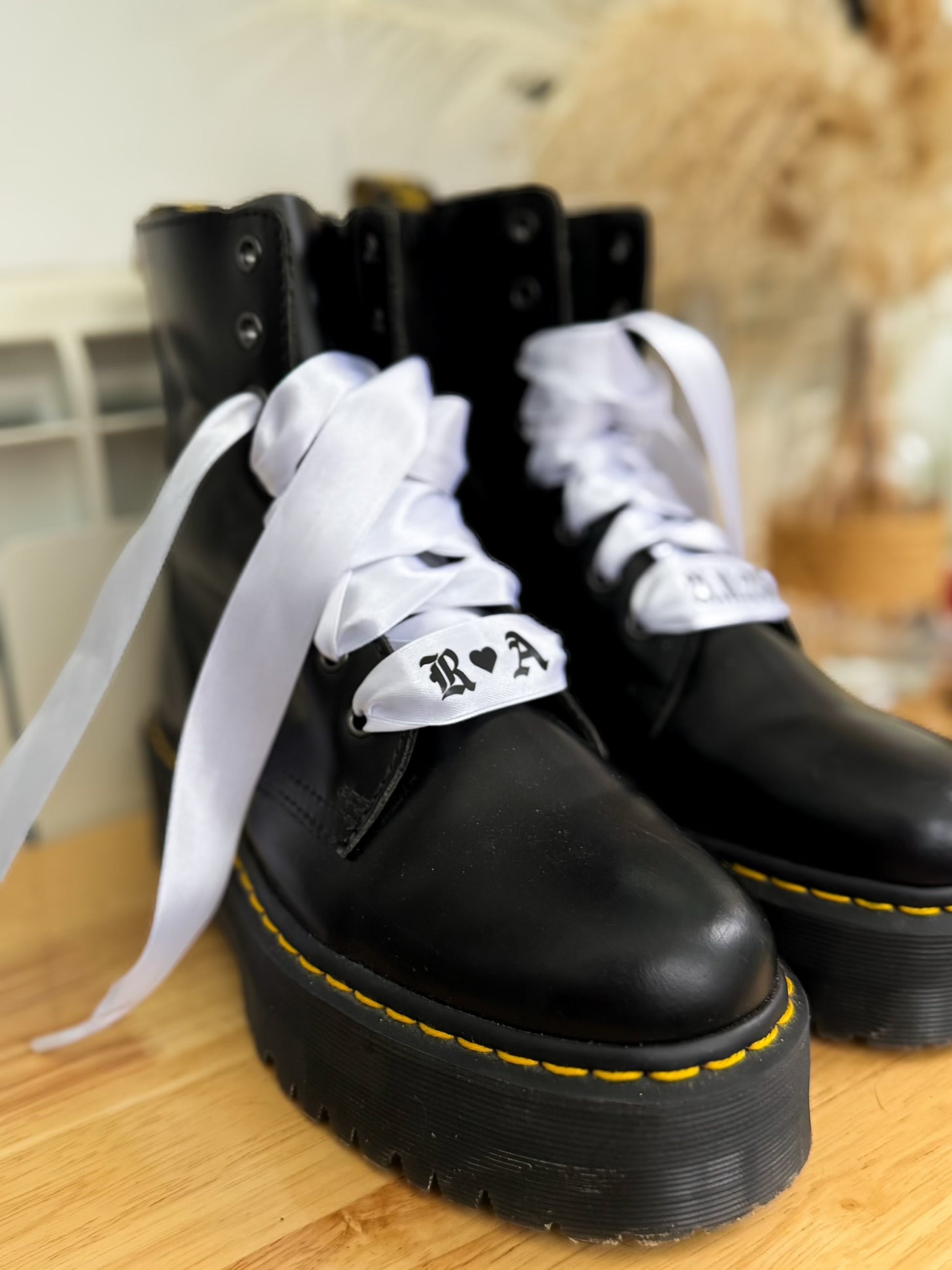 Custom white satin bridal boot laces printed with couple’s initials and wedding date, styled on Dr. Martens for a modern bridal look.