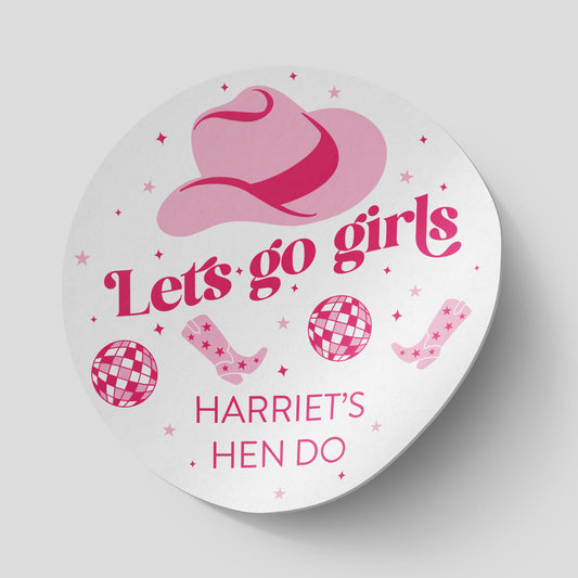 Round sticker with a pink cowboy hat and the text 'Let's go girls' in bold pink font. The design includes pink cowboy boots, disco balls, and stars, with 'Harriet's Hen Do' written at the bottom. Perfect for a fun, themed hen party