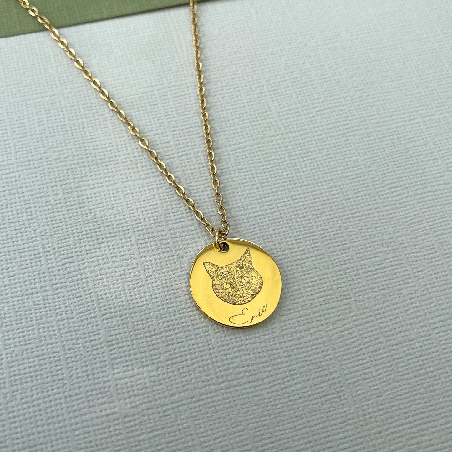An example of a personalised necklace. A gold necklace with a cat engraved with the name Eric  below.