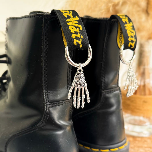 Close-up of silver skeleton hand boot charm  on black dr marten boots