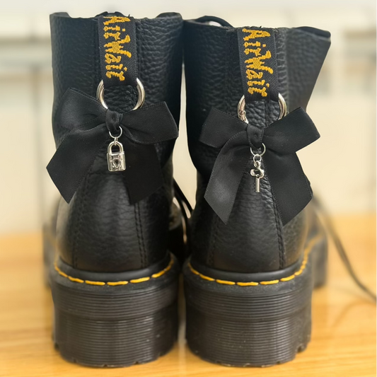 Black boots with black bows and silver locks on a wooden surface