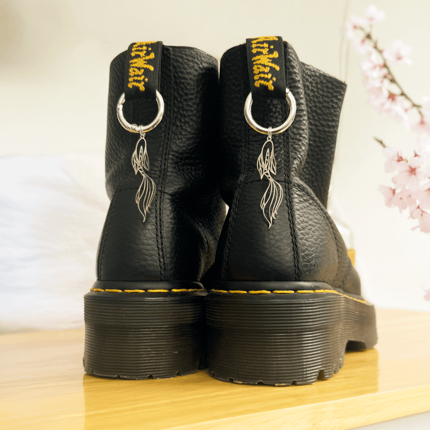 Black boots with unique koi fish charms on a wooden surface
