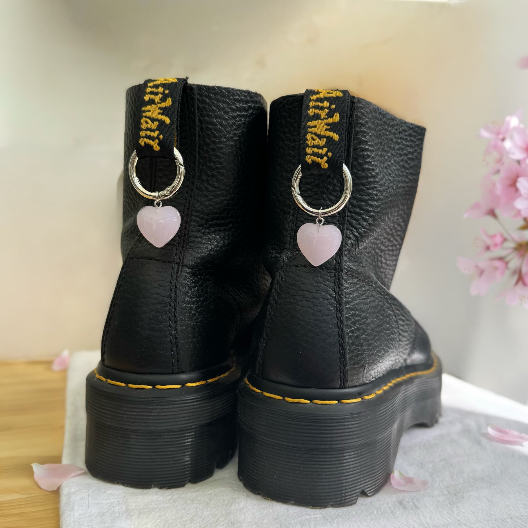 Black boots with heart-shaped boot charms on a light background