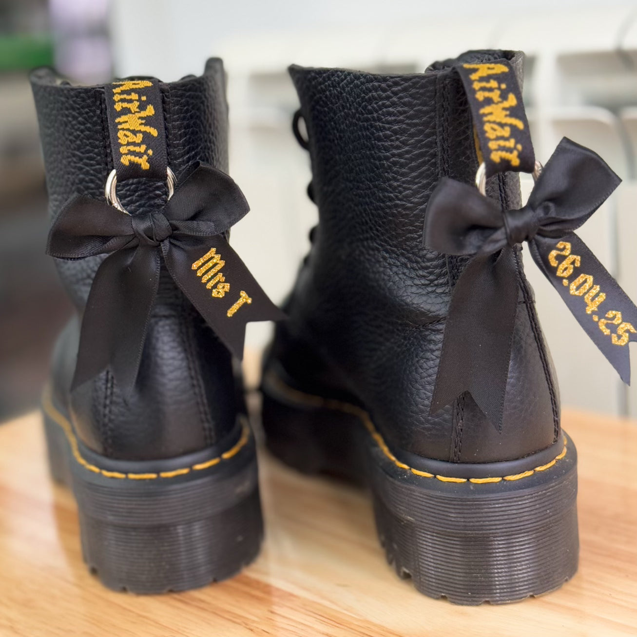 Close up of personalised black boot bows with gold glitter text